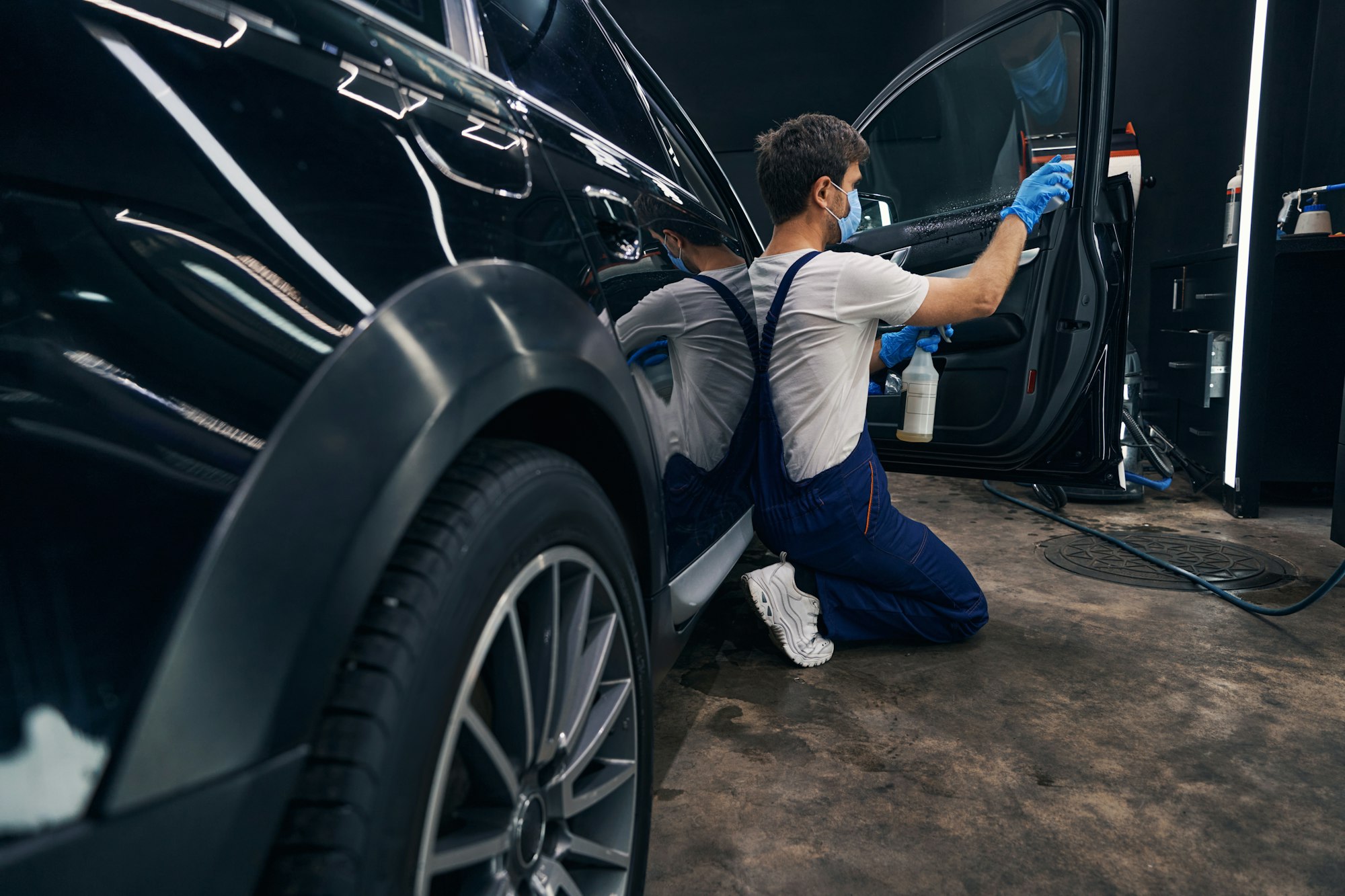 man in repair workshop washing car window during car valeting.jpg